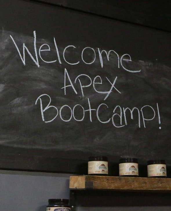 Chalkboard sign reading 'Welcome Apex Bootcamp!' above supplement shelves at Apex Performance Gym in Rockland County, NY.