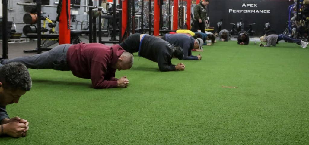 Cross-training participants maintain plank positions, highlighting group fitness and core conditioning