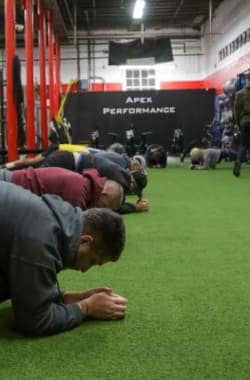 Group of Apex Performance Gym attendees holding plank positions in a cross-training class, showcasing endurance and stability.