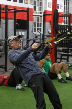 Man engaging in a TRX row exercise in cross-training class, enhancing upper body strength.