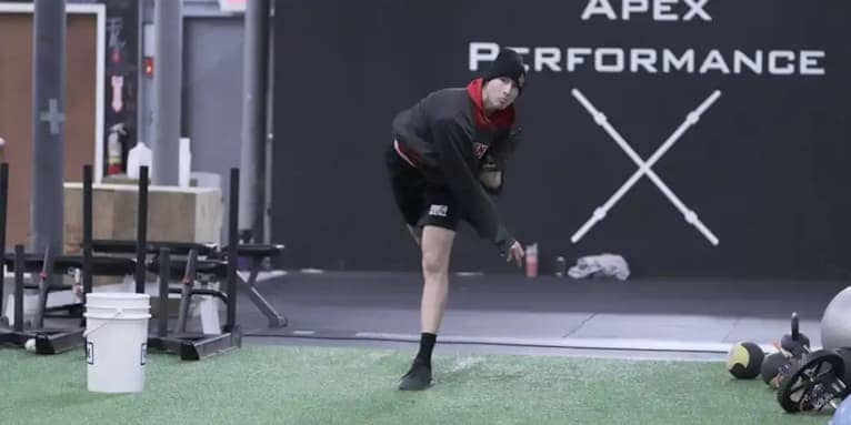 Focused individual performing pitching practice on artificial turf at Apex Performance Gym