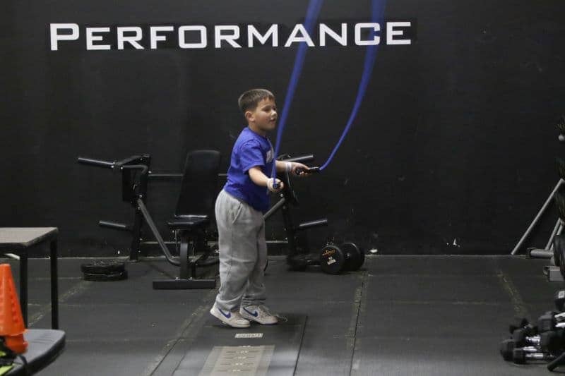 A child energetically performing battle rope exercises at Apex Performance Gym, engaging in a youth-centric fitness program.