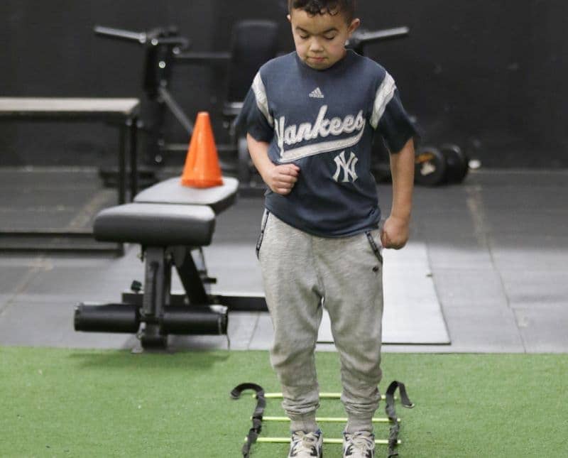 Young gym-goer at Apex Performance Gym poised to begin agility ladder drills, part of the gym's commitment to fostering athletic skills in youth.