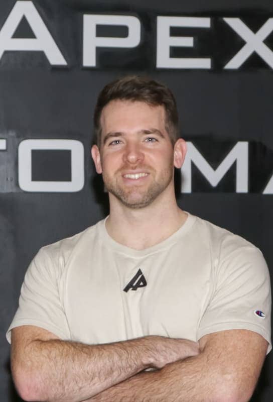 Cross training coach Brendan Sullivan smiling in a tan apex branded shirt.