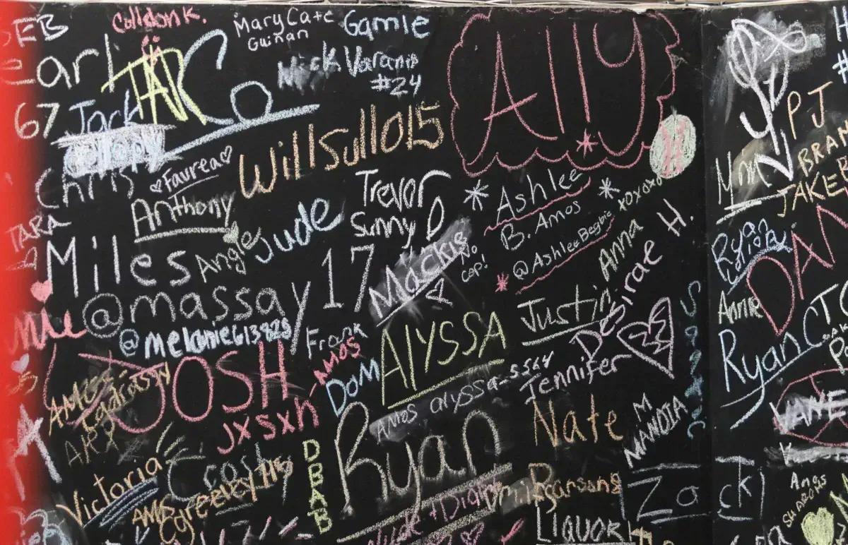 Community wall at Apex Performance Gym filled with chalk signatures and messages from members, celebrating their commitment to fitness.