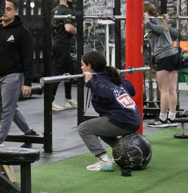 Athlete performing a barbell squat at Apex Performance Gym, emphasizing strength training in action.